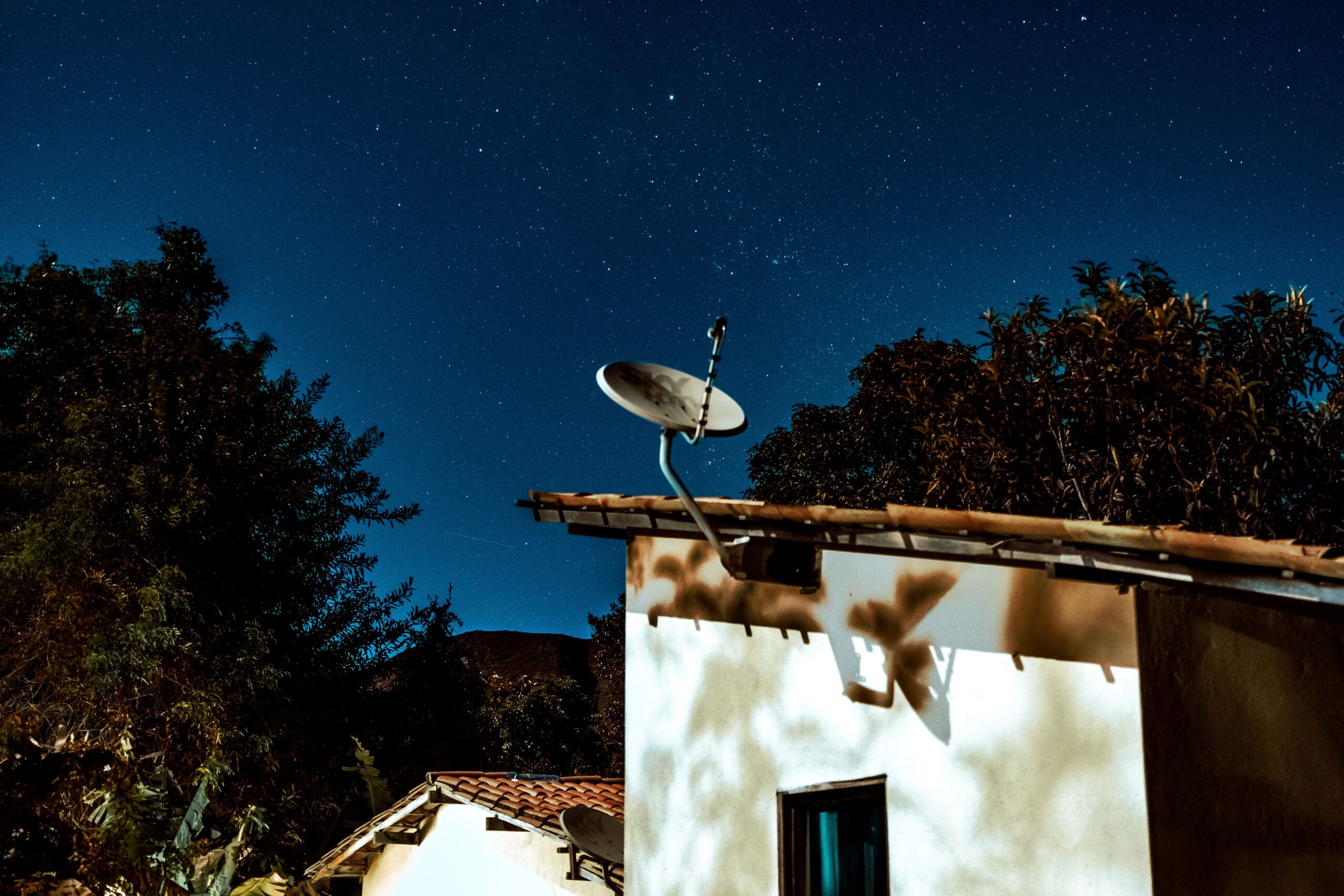 Satellite internet dish under a starry night sky on remote land