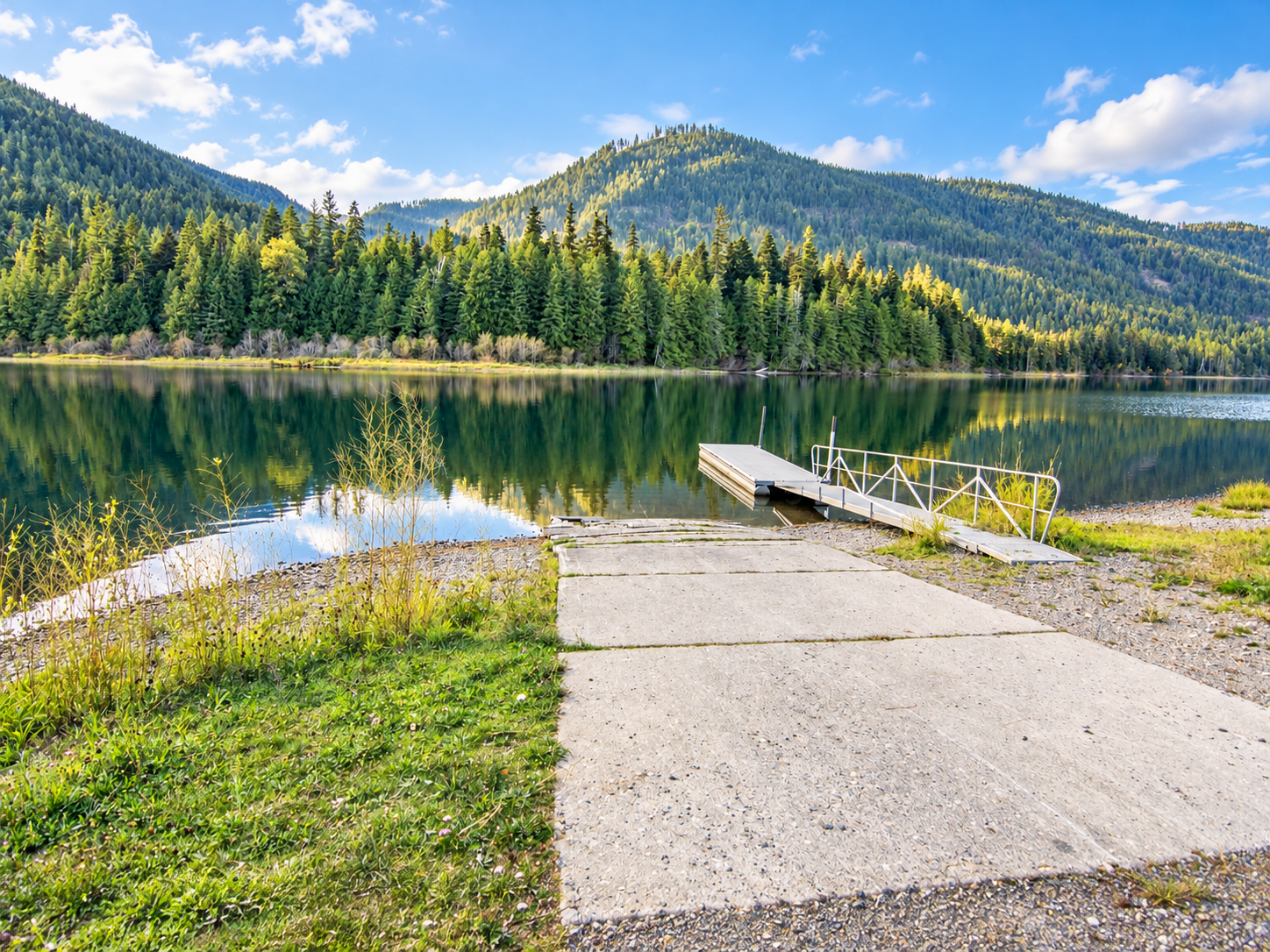 Concrete boat launch and floating dock on Bull Lake with wooded mountains across the water
