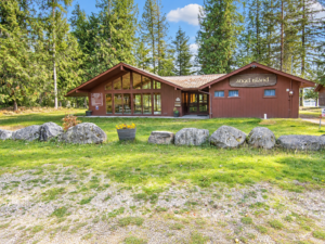 Angel Island community clubhouse exterior with lawn, stone landscaping and tall trees near Bull Lake