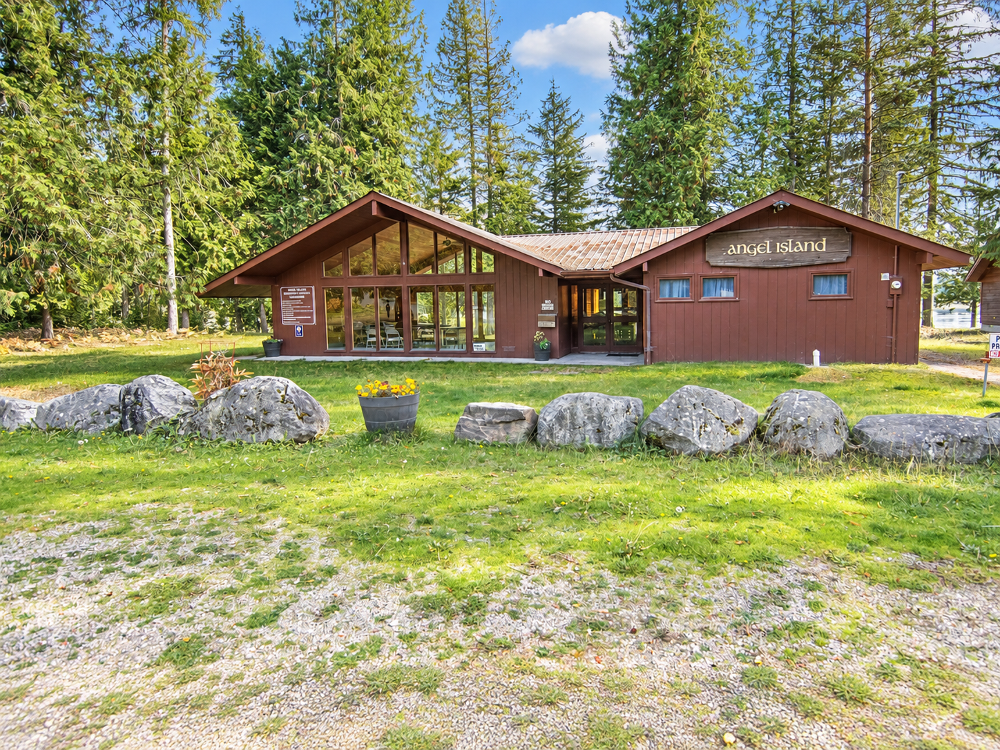 Angel Island community clubhouse exterior with lawn, stone landscaping and tall trees near Bull Lake