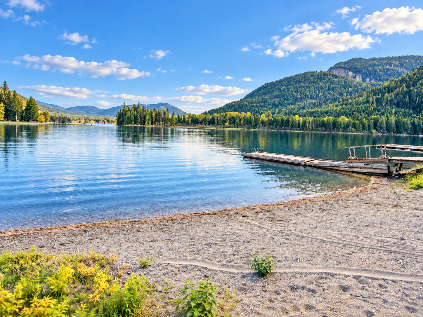 Sandy Bull Lake beach and wooden dock with clear water and forested mountains across the lake
