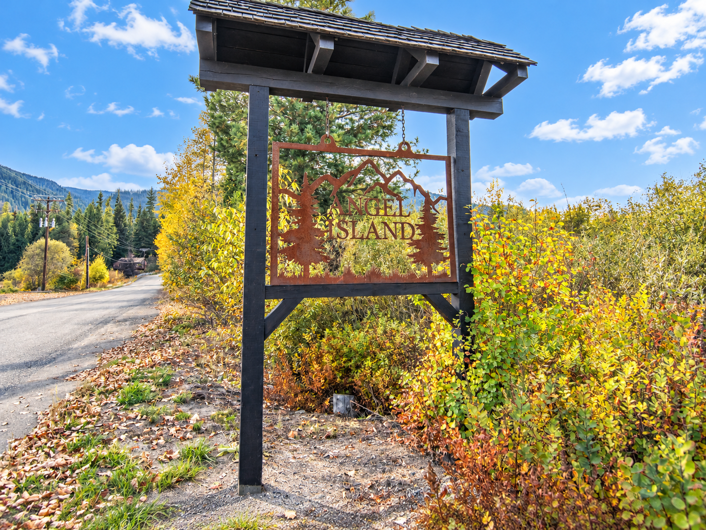 Angel Island entrance sign beside a paved road with golden autumn foliage near Bull Lake, Montana