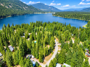 Drone view of Bull Lake, wooded Angel Island community roads and mountains in Lincoln County, Montana