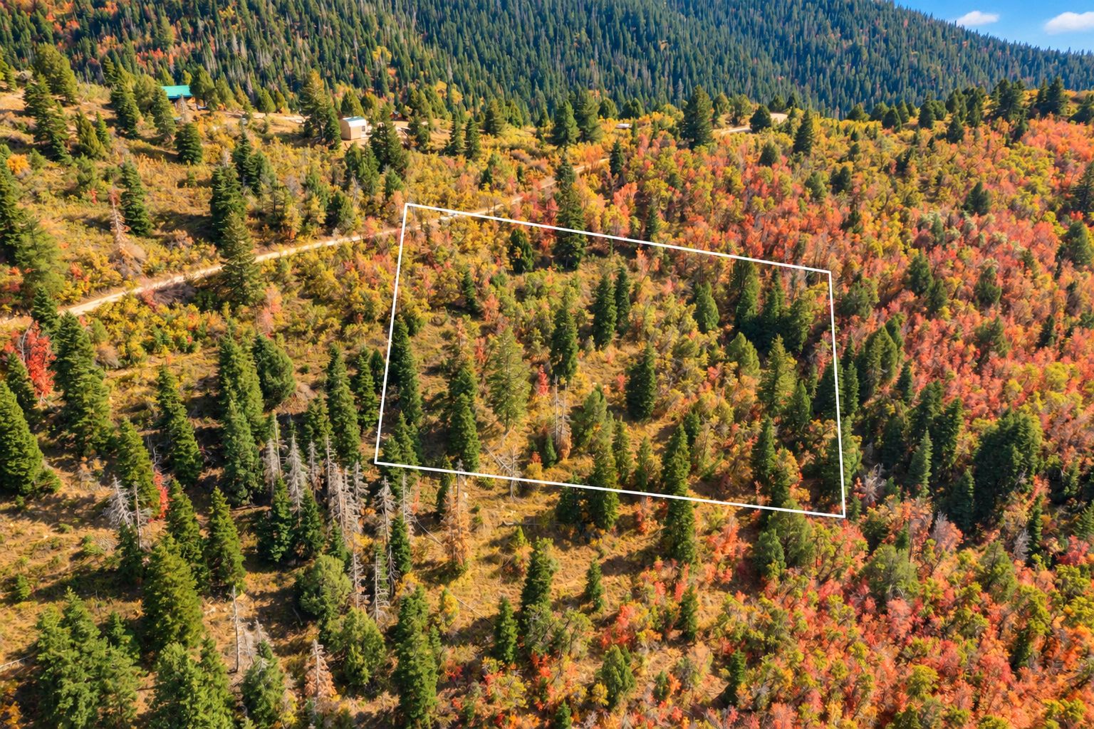 Angled aerial view of the wooded 5-acre parcel near Strawberry Point, Utah, with nearby dirt-road access